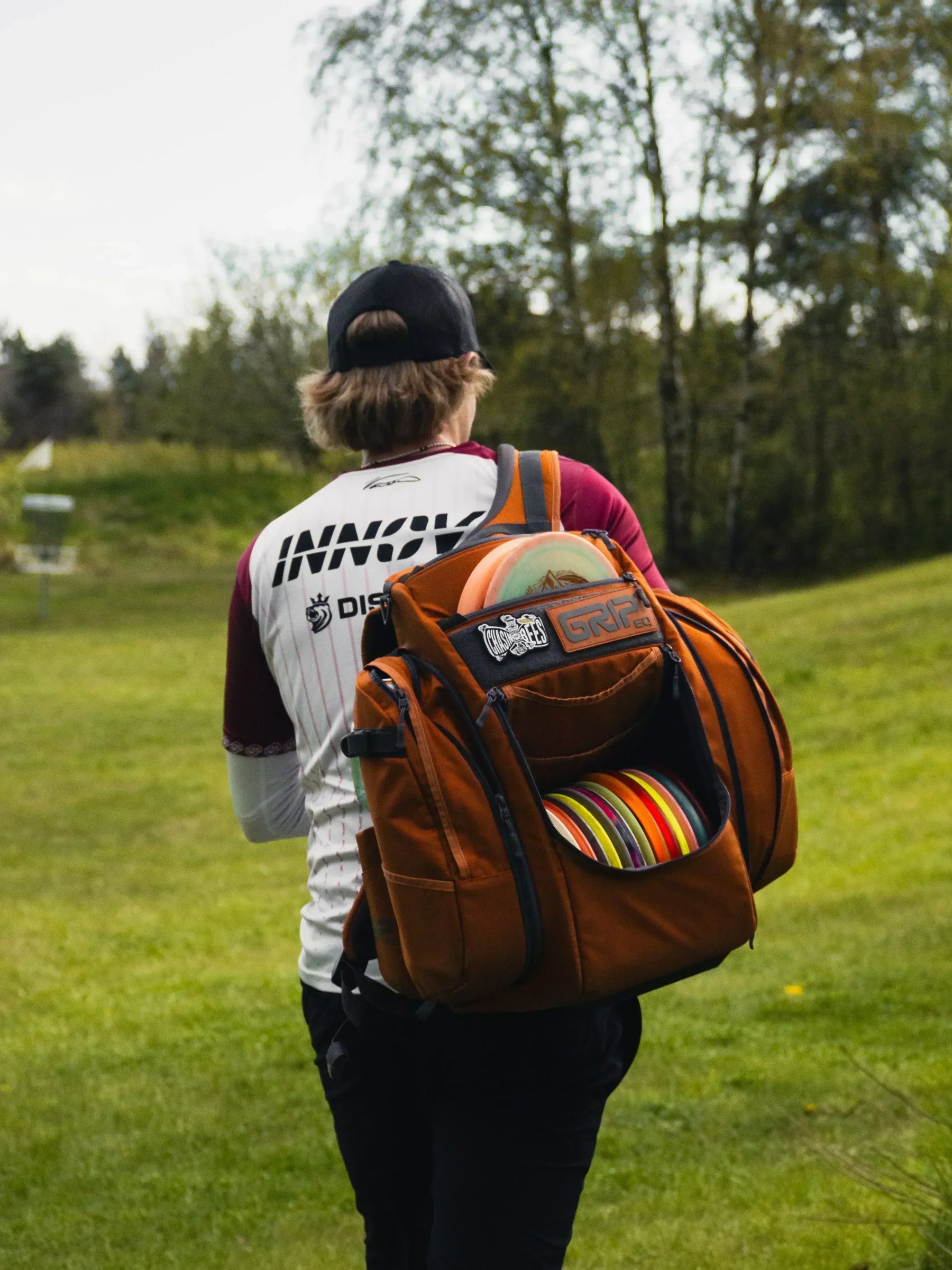 Väinö Mäkelä kävelee frisbeegolfradalla bägi selässä.